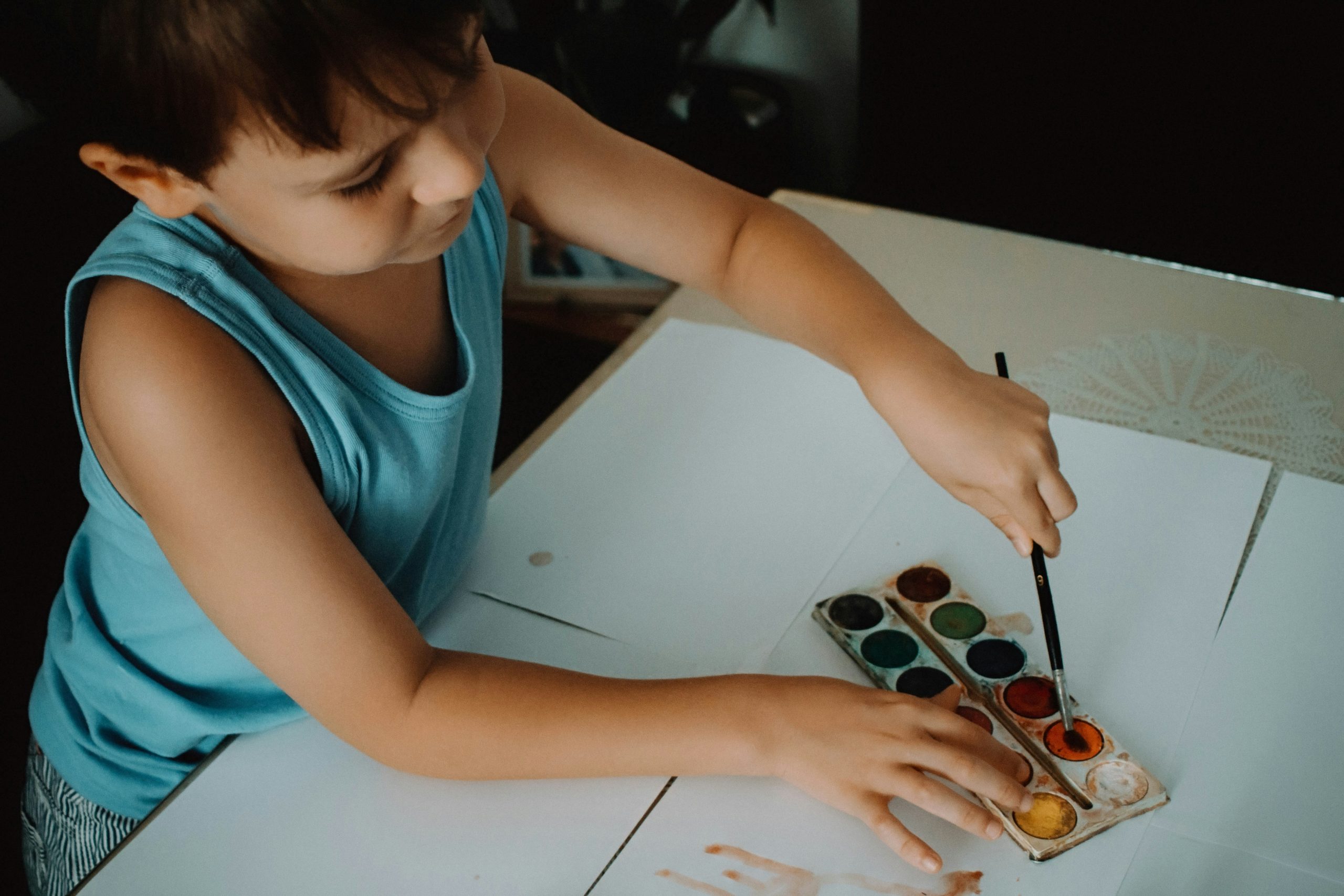 Child painting during a school art class, developing focus and patience through creative work