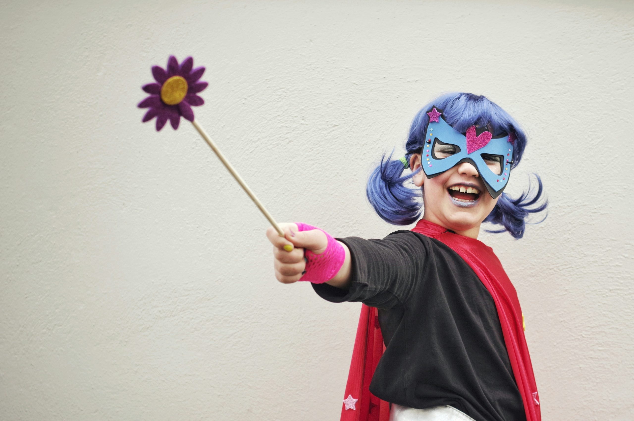 A young child in a superhero cape mid-imaginative play