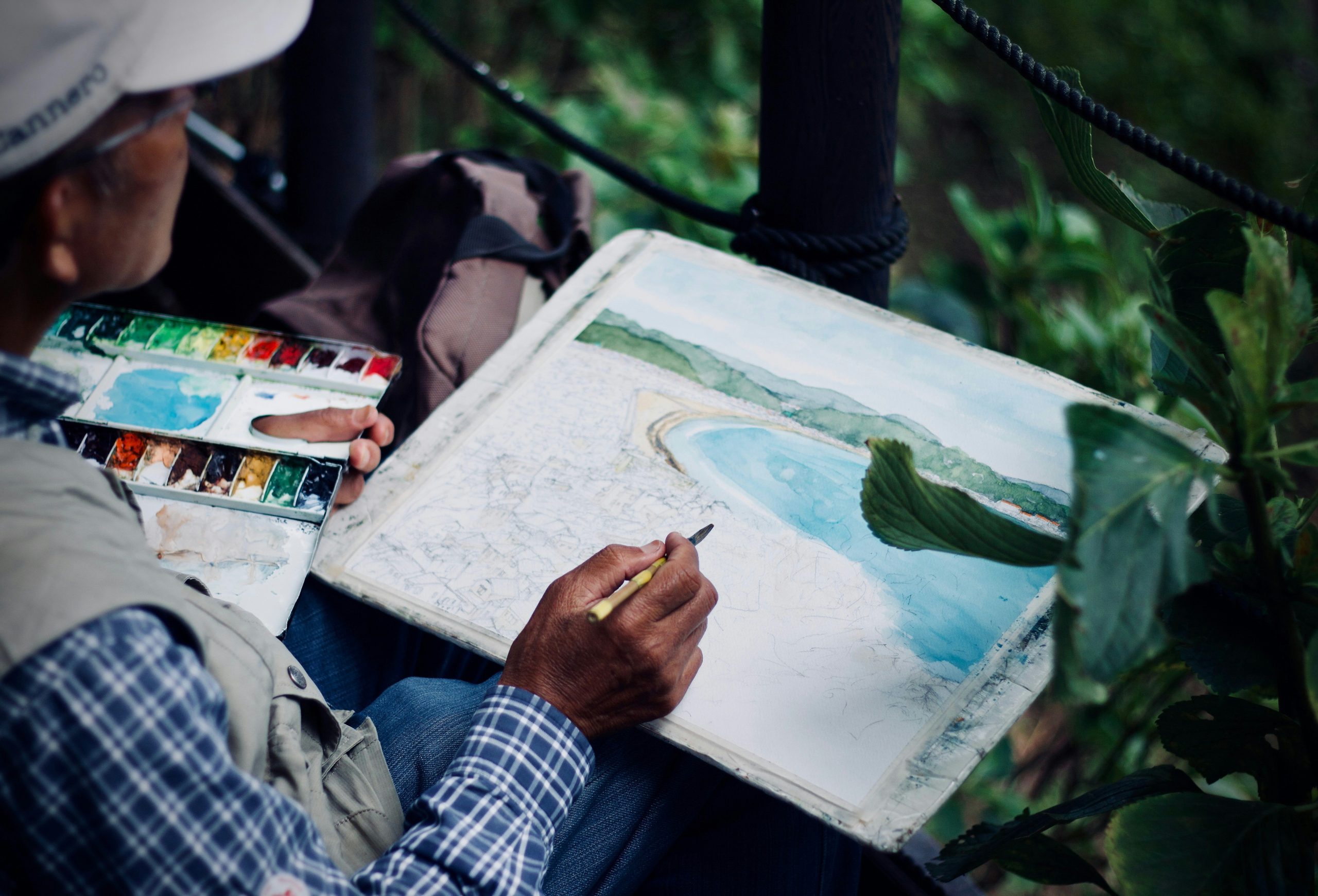 A person painting a seascape outdoors in their own time, away from work
