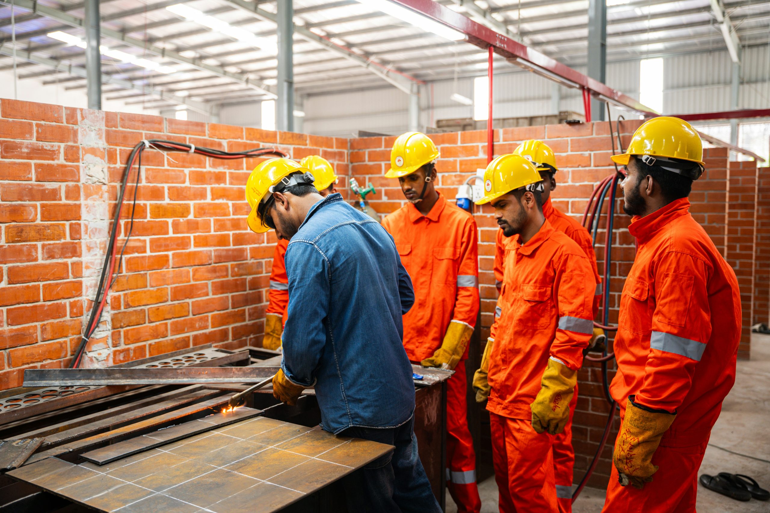 Workers in hard hats and safety vests collaborating in a workshop, representing hands-on vocational training